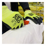 A worker wearing MCR Safety Cut Pro 18 Ga HyperMax Hi Vis Nitrile Micro Dotted Gloves (92748HV) uses a red utility knife to cut white material, possibly in an industrial or warehouse setting.