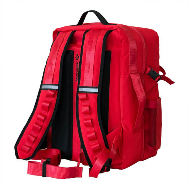 The Aero Healthcare Modulator Trauma Backpack M600B is shown from the back, displaying padded shoulder straps, black accents, a chest strap, and side pockets. The bright red backpack stands upright against a plain white background.