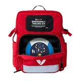 A red Aero Healthcare Modulator Trauma Backpack M600B with a partially open front pocket reveals a defibrillator inside. It features an emergency trauma kit label, reflective strip, and meets ANSI Class B First Aid Kit standards.