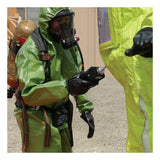 Two people in green hazmat suits, gloves, and breathing apparatuses are working outdoors during a HazMat Response. One holds a RAE Systems PpbRAE 3000 Monitor while facing the other person, who is partially visible.