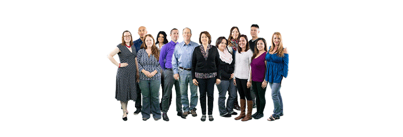 A diverse group of thirteen people standing together, smiling at the camera. They are dressed in casual and smart-casual attire, with a white background.